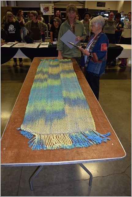 Judge Kathy Nelson and Rolly Thompson review Team Bees second place Shawl. Photo: Rich Lundquist.